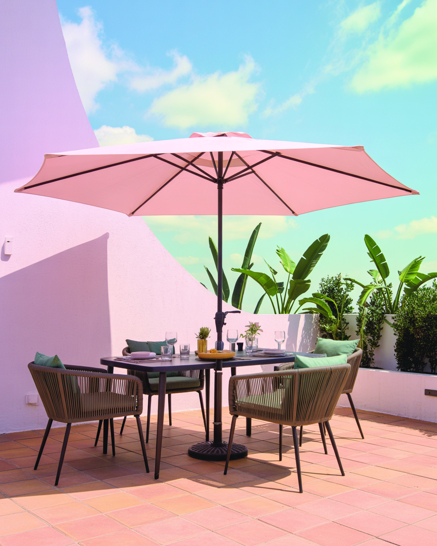 Freestanding outdoor umbrella providing shade on an apartment balcony with a dining set.