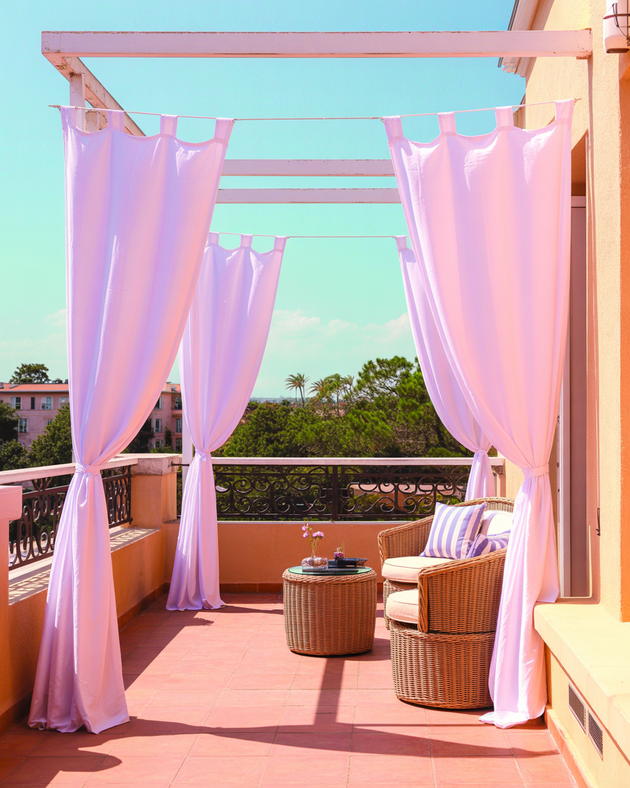 Outdoor curtains on an apartment balcony offering shade and privacy in a chic, relaxed setting.