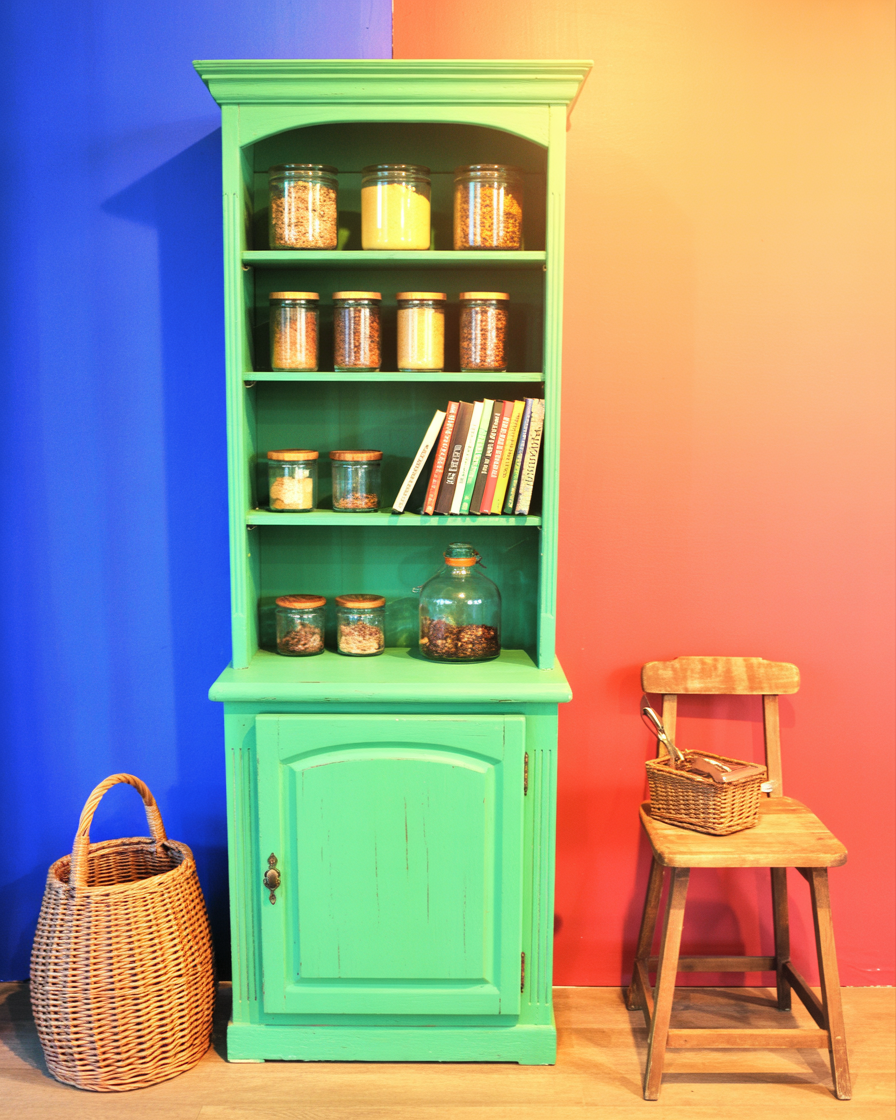 Painted bookshelf styled as open pantry storage with jars and baskets