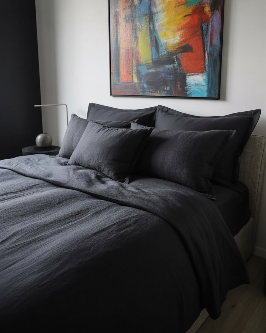 Black linen bedding paired with colorful art for a dynamic and modern bedroom aesthetic.