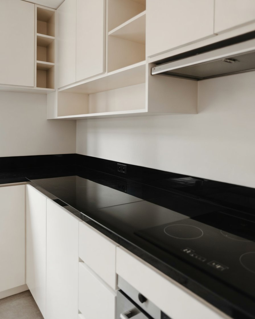 A chic black-and-white kitchen with glossy countertops and minimalist shelving.