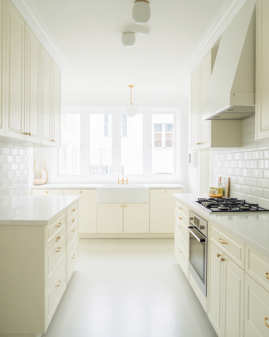 A bright and fresh all-white kitchen with gold hardware and a minimalist design.